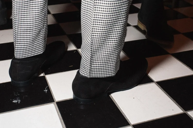 Guests in houndstooth trousers on the black-and-white checkered floor during an event