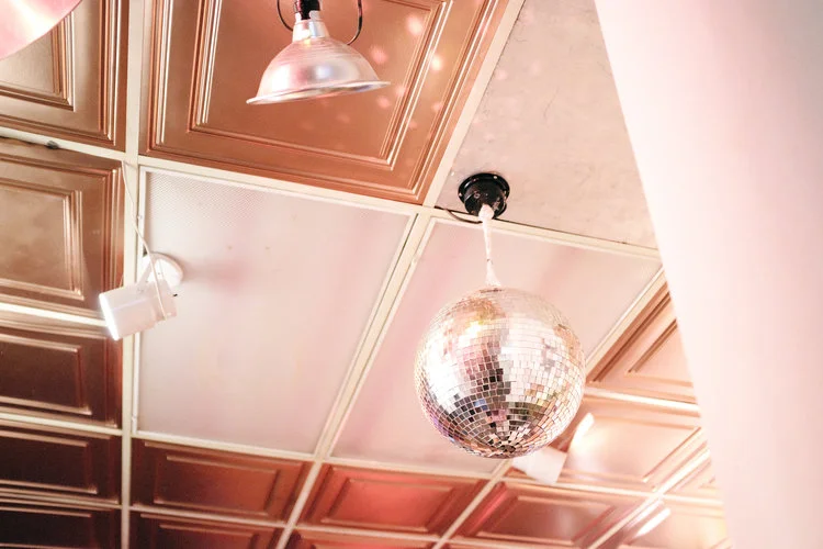 Disco ball hanging from copper ceiling tiles in the Chinatown Soup venue