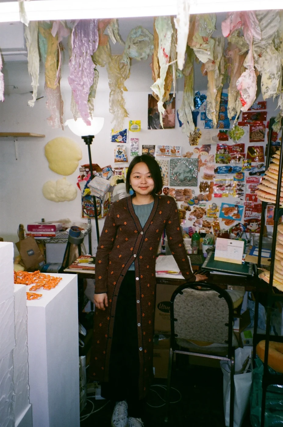 A resident standing in her studio under hanging fabric sculptures