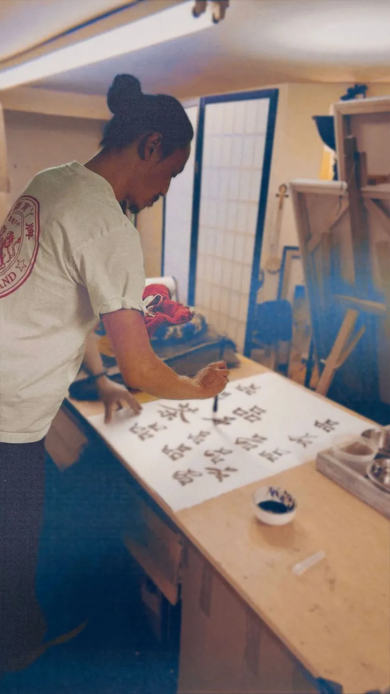 A resident practicing calligraphy with brush and ink