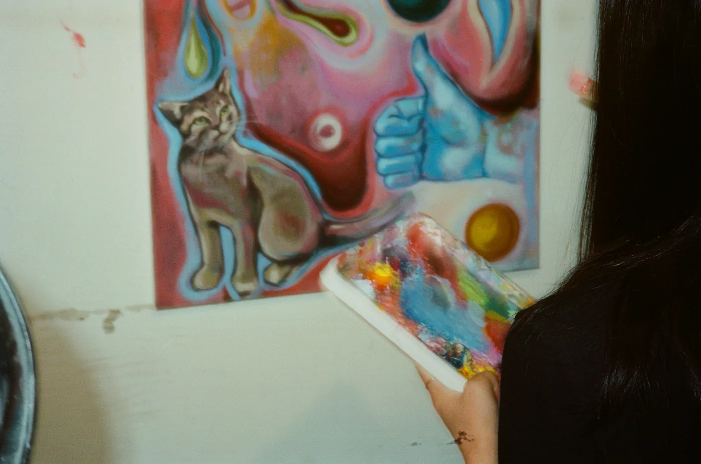 Palette in hand while painting a surreal canvas in the studio