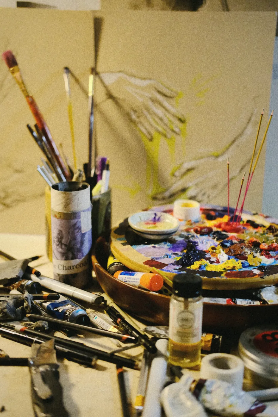 Wooden palette, brushes, and a hand study on the studio desk