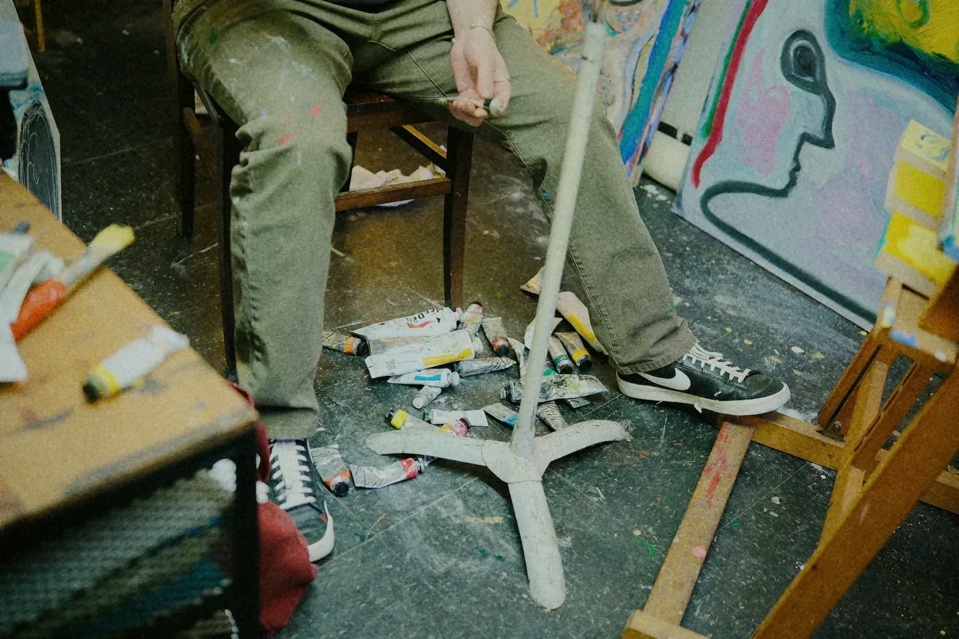 Paint tubes scattered on the studio floor under an easel