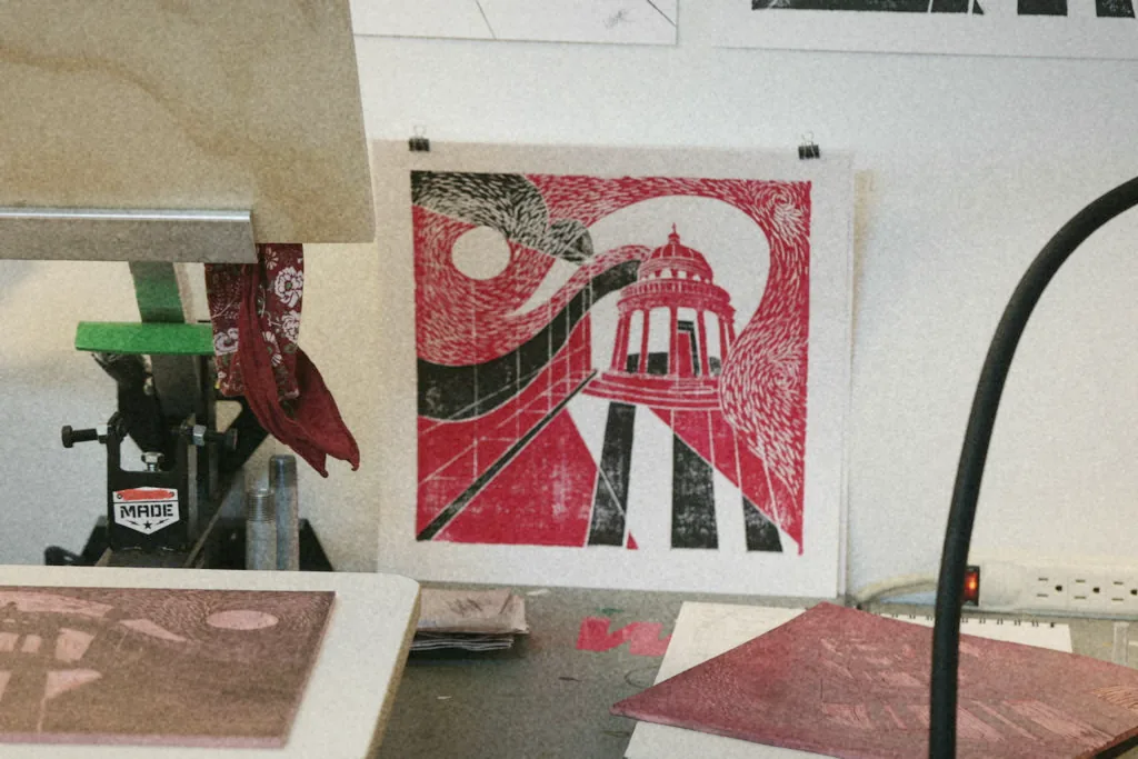 Printmaking press, plates, and a finished print on the wall