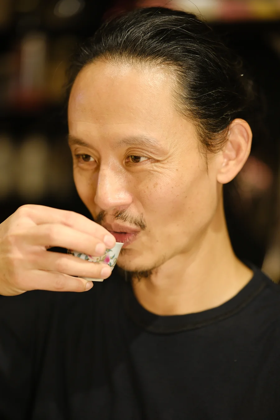 A man sipping tea from a small painted cup